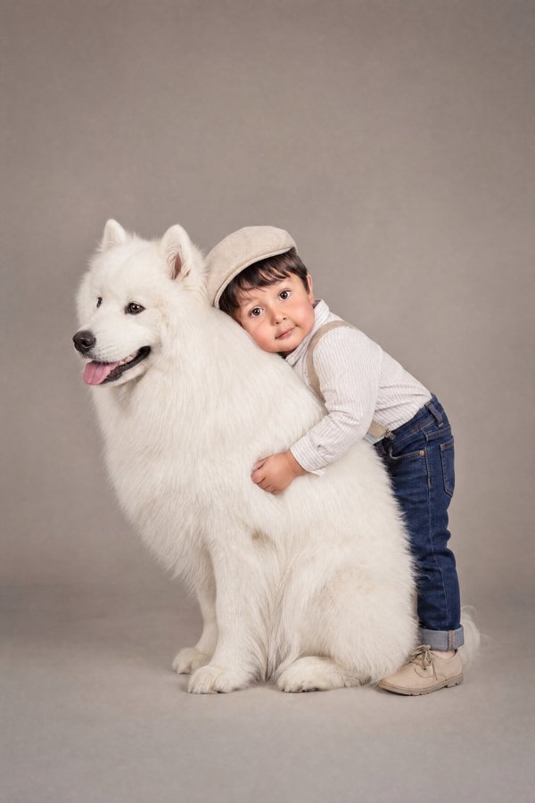 Retrato infantil con gorra junto a un perro blanco