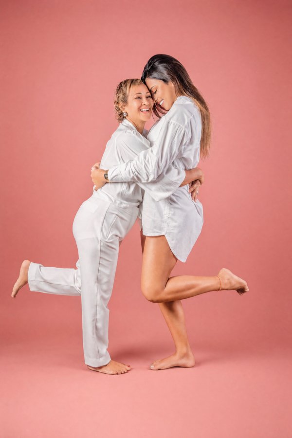 Abrazo familiar con vestuario blanco sobre fondo rosado