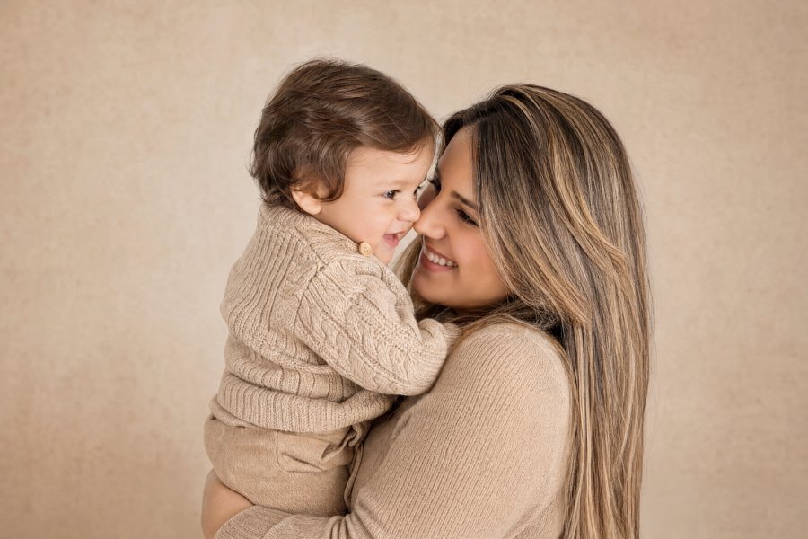 Madre abrazando a su hijo con ropa en tonos beige