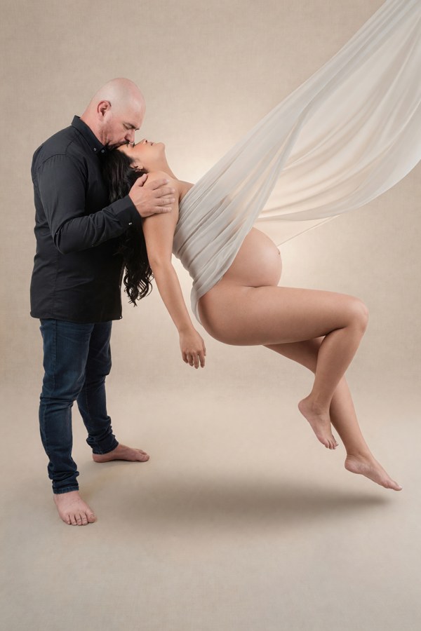 Retrato de maternidad en pareja con velo blanco suspendido