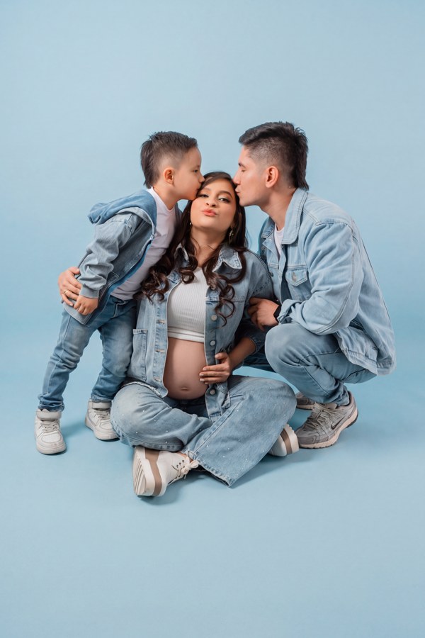 Madre embarazada recibiendo besos de su pareja y su hijo