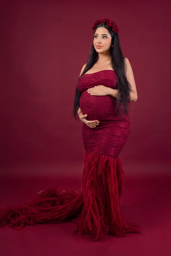 Retrato de maternidad con vestido y flores en tonos vino