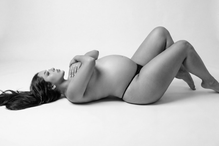 Retrato artístico de maternidad recostada en blanco y negro