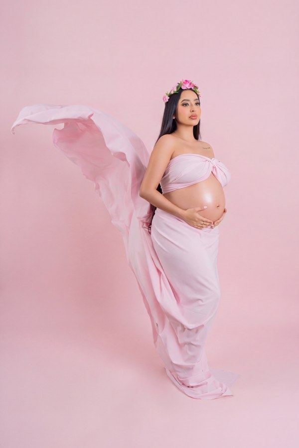 Retrato de maternidad con telas y flores rosadas